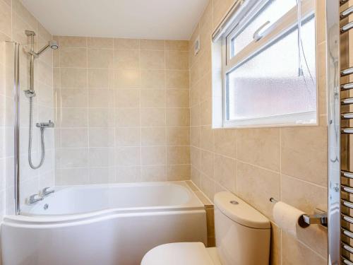 a bathroom with a tub and a toilet and a window at 2 Bed in Bude 82163 in Bude