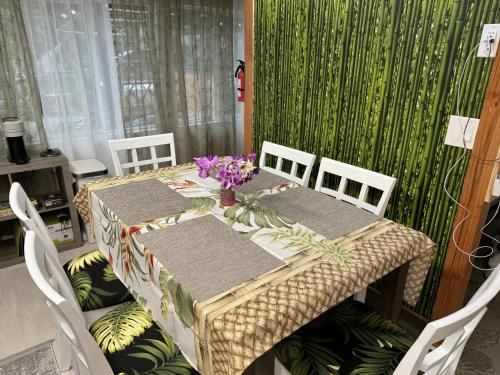 a table with chairs and a table with flowers on it at Secluded house, Opening special in Pahoa