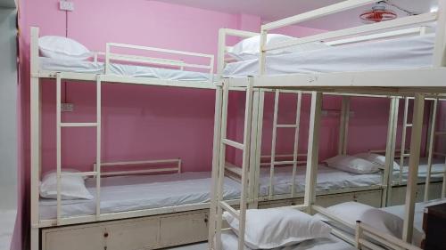 two bunk beds in a room with pink walls at BASERA HOSTEL DORMITORY in Alambagh