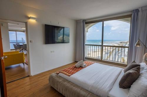 1 dormitorio con 1 cama y balcón con vistas al océano en The Blue Lagoon With Pool By Nimizz, en Tel Aviv