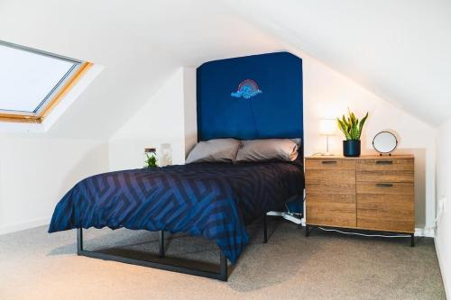 a bed with a blue headboard in a room at Spacious 2BD Maisonette with Lush Loft in Newquay in Newquay