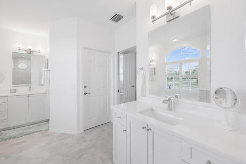 Baño blanco con lavabo y espejo en 101 Landmark Street, en Marco Island