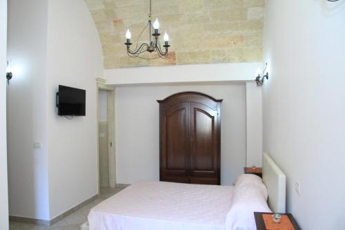 a bedroom with a bed and a chandelier at Corte Della Luna in Acquarica del Capo