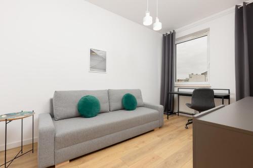 a living room with a gray couch with green pillows at Minimalist Apartment in Łódź With Parking Near Łódź Kaliska by Renters in Łódź