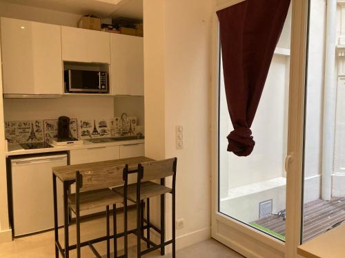 eine kleine Küche mit einem Tisch und einem Fenster in der Unterkunft Charmant studio au coeur de Paris in Paris