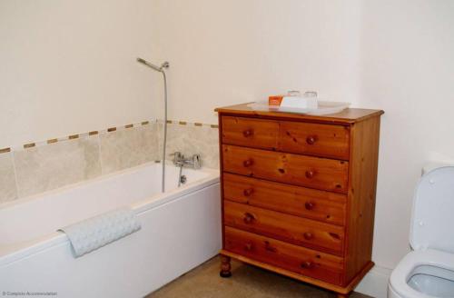 a bathroom with a bath tub and a wooden dresser at Pleasure Row in Alton