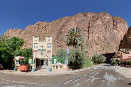 a building on the side of a road in front of a mountain at Hotel De La Vallée in Aït Baha