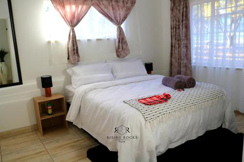 una camera da letto con un grande letto bianco con sopra oggetti rossi di Tranquil Mountain Cottage :Hikes/Boma/Animals/Pool a Magaliesburg