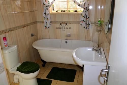 y baño con bañera, aseo y lavamanos. en Tranquil Mountain Cottage :Hikes/Boma/Animals/Pool, en Magaliesburg