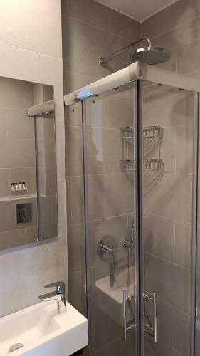a shower with a glass door next to a sink at Hotel Plaza in Kalamata