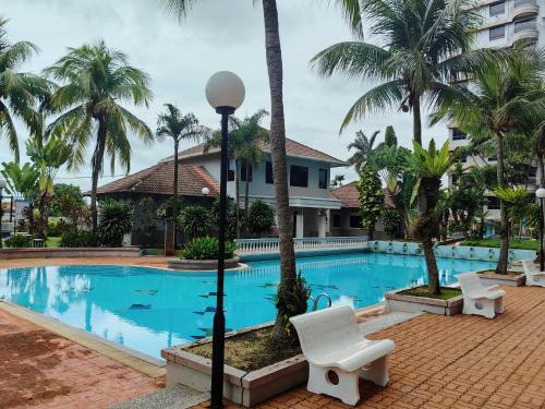 uma piscina de resort com uma cadeira branca e palmeiras em Klebang GX Homestay Resort Pool View P0804 with Netflix, TVBox and Games em Malaca