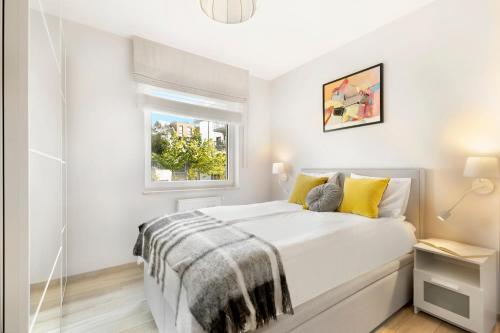 a white bedroom with a bed and a window at Elite Apartments Malczewskiego 109 in Gdańsk