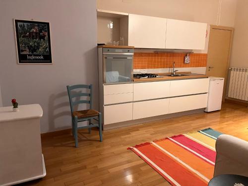 eine Küche mit weißen Schränken und einem Stuhl in einem Zimmer in der Unterkunft A Casa di Eugenia in Battipaglia