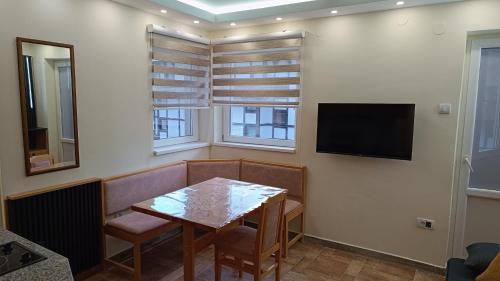 a dining room with a table and a flat screen tv at Vila Plan Karaman greben in Raška