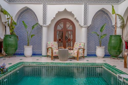 una piscina en una casa con sillas y plantas en Riad Ekla Boutique Hotel, en Marrakech