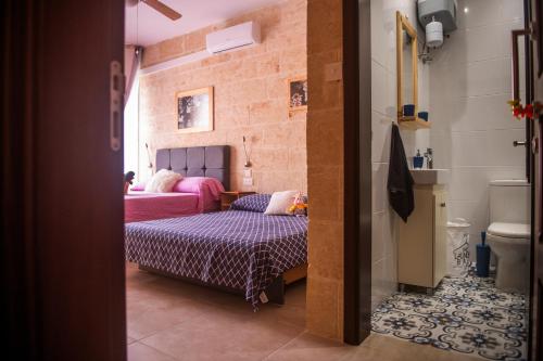 a small bedroom with a bed and a bathroom at C'Est La Vie in Xagħra