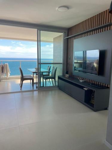 a living room with a table and chairs and the ocean at DUETTO Barra in Salvador