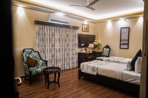 a hotel room with a bed and a chair at The Vaishnavi in Deoghar
