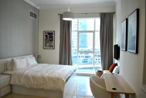 a white bedroom with a bed and a window at Amazing View I 1min Walk to Marina Mall I Close to Beach in Dubai