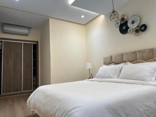 1 dormitorio con cama blanca y reloj en la pared en Central Park House - 70m², en Mohammedia