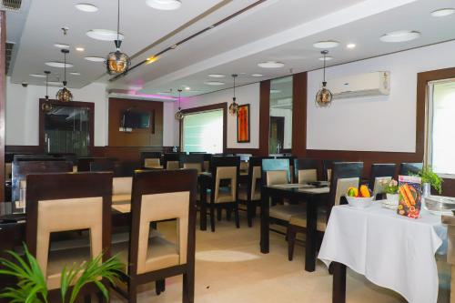 a dining room with tables and chairs and a screen at The Vaishnavi in Deoghar