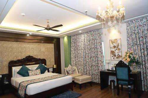 a bedroom with a bed and a desk and a chandelier at The Vaishnavi in Deoghar