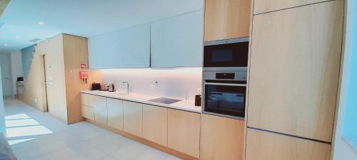 a kitchen with wooden cabinets and a stove at Villa Central By Garvetur in Quarteira