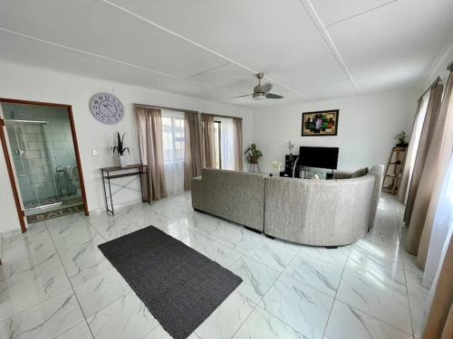 uma sala de estar com um sofá e um relógio na parede em Luxury 1 Bdr Garden Cottage em Windhoek