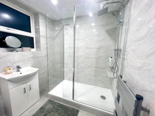 a white bathroom with a shower and a sink at 4BR House for Contractors in New Bilton