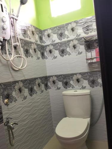 baño con aseo y flores en la pared en Nik Homestay en Tanah Merah