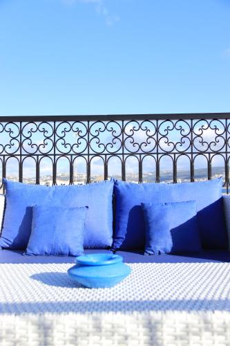 a bed with blue pillows and a blue plate on it at Riad Zhor Tanger - Médina in Tangier