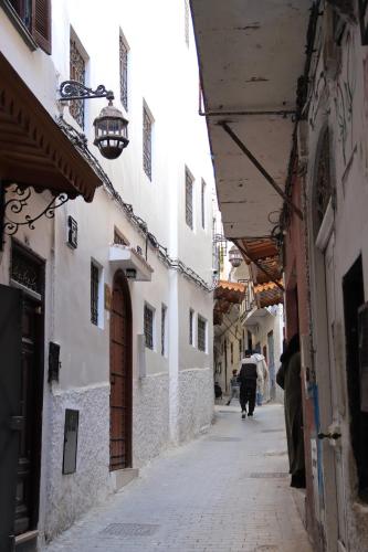 an alley with a person walking down a street at Riad Zhor Tanger - Médina in Tangier