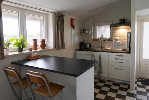 een keuken met een zwart aanrecht en 2 stoelen bij Op d'n Stolberg in Weert