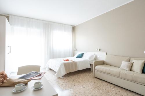 a white bedroom with a bed and a couch at Residence Sabrina in Ceriale