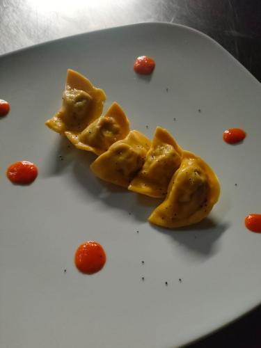 a white plate with ravioli and tomatoes on it at Hotel Bristol in Fiumalbo