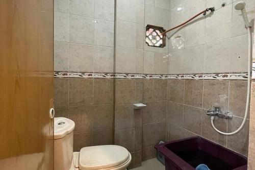 a bathroom with a shower with a toilet and a tub at Hotel O Homestay Pakmuklis Syariah 2 Near Taman Mini Lhokseumawe in Lhokseumawe