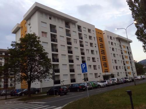 a large white building with cars parked in a parking lot at Apartman Appetito Banja Luka in Banja Luka