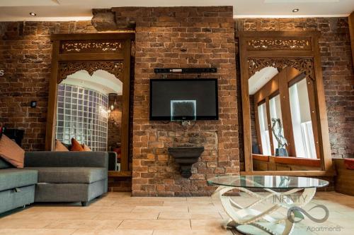 a living room with a couch and a tv on a brick wall at Infinity PartyPadsLiverpool Hen and Stag Welcome in Liverpool