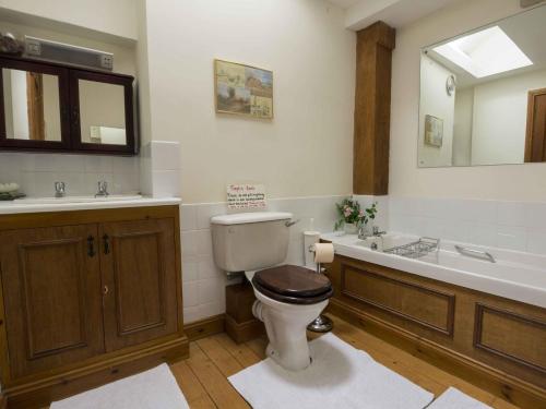 a bathroom with a toilet and a sink and a tub at The Granary Ruthwaite in Uldale