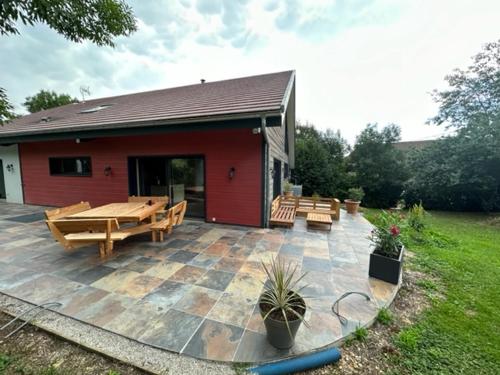 a patio with picnic tables and benches in front of a house at LES ANTHOCYANES CHAMBRE MONTAGNE in Champagny