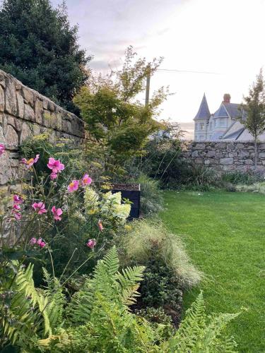 a garden with pink flowers and a stone wall at New build eco house in walled garden, Rostrevor in Rostrevor