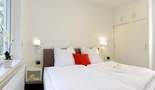 una camera da letto con un letto bianco con cuscini rossi di Seeresidenz Haus Nordic a Bansin