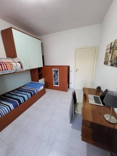a room with a bed and a desk with a laptop at Happy Ladispoli - Vista Mare in Ladispoli