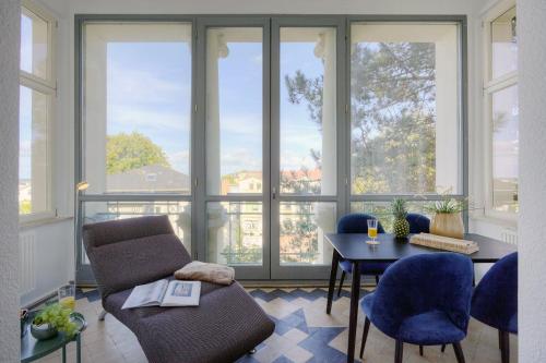 a living room with a table and chairs and windows at Villa Schlossbauer Nr 09 in Heringsdorf