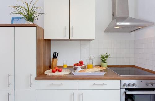 ヘリングスドルフにあるVilla Schlossbauer Nr 09の白いキャビネット、カウンターの果物と野菜が備わるキッチン