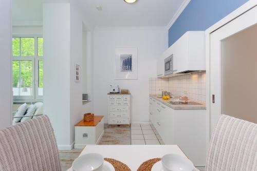 uma cozinha com armários brancos e uma mesa e cadeiras em Villa Waldstraße Nr 09 em Bansin
