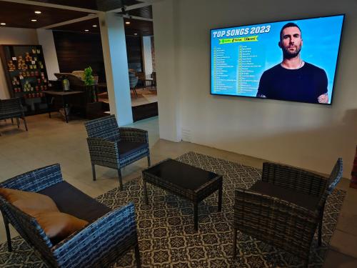 a waiting room with chairs and a tv on the wall at The Guest Hotel & Hostel in Chiang Mai