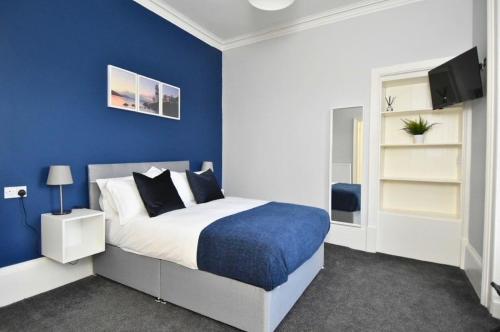 a blue bedroom with a bed and a tv at The Cloch in Gourock