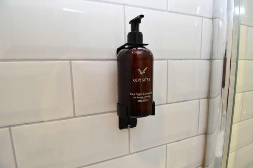 a bottle of soap is hanging on a tiled wall at The Cloch in Gourock