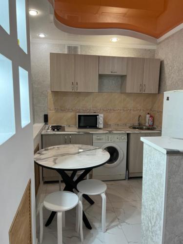 a kitchen with a table and two stools at Апартаменты Экибастуз in Ekibastuz